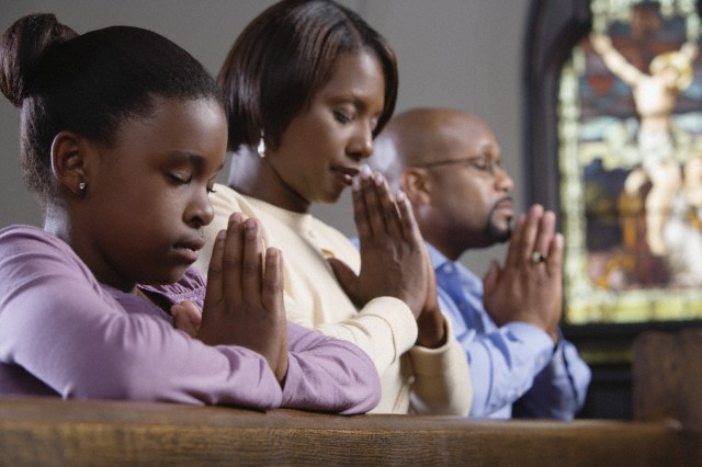 Family praying in church --- Image by © Ocean/Corbis